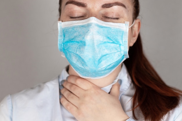 Dolor de garganta. Chica joven con una máscara médica se siente mal.