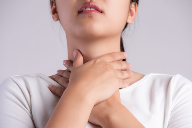 Foto dolor de garganta. primer plano de la mano hermosa joven tocando su cuello enfermo.