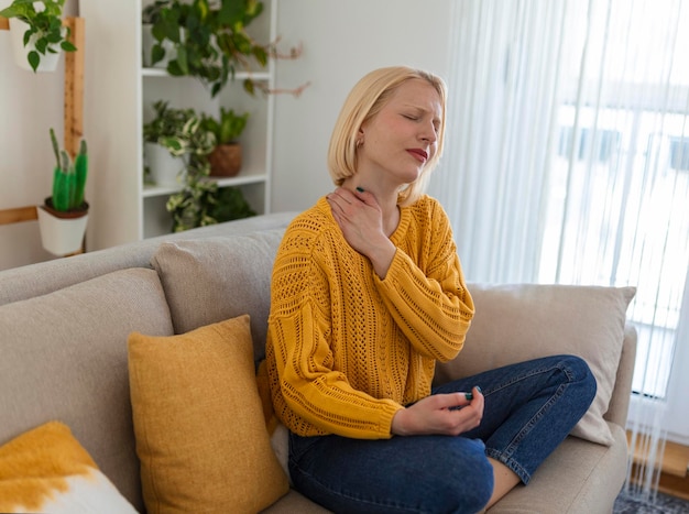 Dolor en el hombro Dolor en la parte superior del brazo Personas con problemas de músculos corporales Concepto de salud y medicina Mujer atractiva sentada en la cama y sosteniendo el hombro doloroso con otra mano