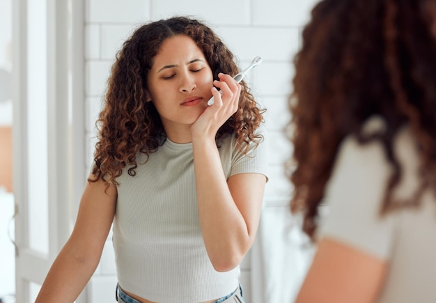 Dolor de muelas dolor oral y sensibilidad dental para una mujer que se cepilla los dientes por la mañana Mujer afroamericana que sufre dolor o inflamación en la boca en el baño