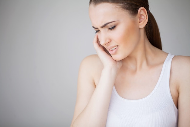 Dolor de muelas. Mujer sintiendo dolor de dientes. Primer de la muchacha triste hermosa que sufre de dolor de diente fuerte. Atractiva mujer sensación dolorosa dolor de muelas. Concepto de salud y cuidado dental