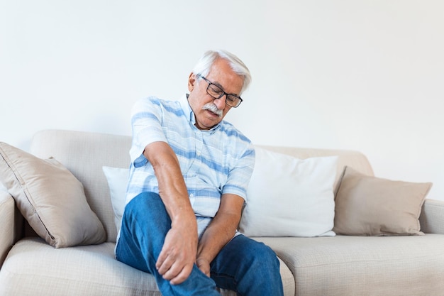 Dolor en la pierna de un hombre anciano Hombre anciano que sostiene un doloroso esguince muscular o dolor de calambre