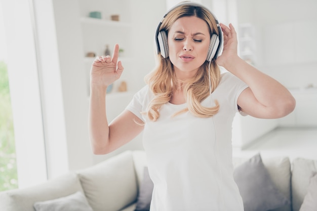 Doméstica bonita dama rubia quédate en casa escucha cool tecnología moderna auriculares