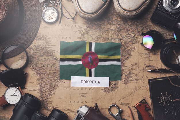 Dominica-Flagge zwischen dem Zubehör des Reisenden auf alter Weinlese-Karte. Obenliegender Schuss