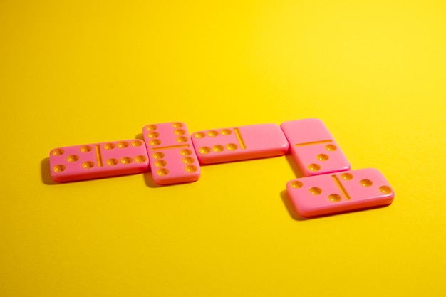 Dominó de jogo de tabuleiro rosa em um fundo amarelo