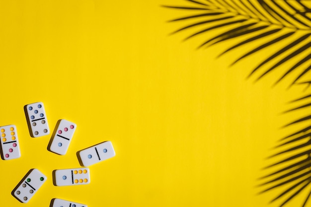 Dominoes blancos con puntos coloridos y un tablero redondo giratorio en un fondo amarillo Juego de mesa