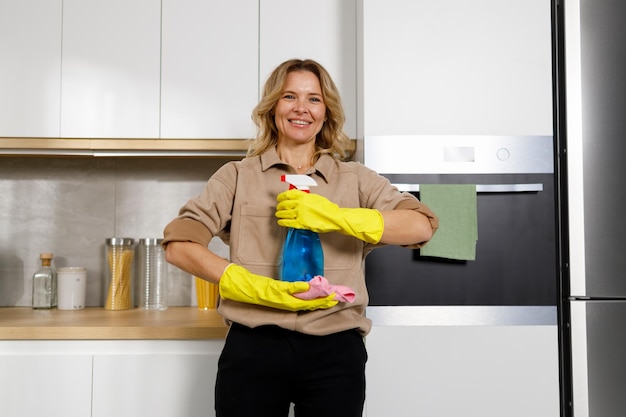 Dona de casa agradável na cozinha segurando produtos de limpeza