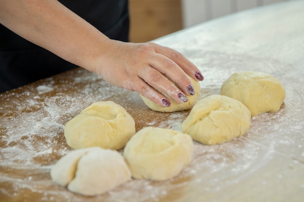 Dona de casa caucasiana prepara massa de pizza em cima da mesa. fechar-se.