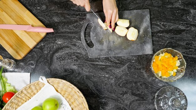 Dona de casa corta maçã cozinhando salada de frutas na mesa da cozinha