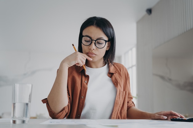 Dona de casa feminina de óculos calcula despesas planejando orçamento doméstico para economizar dinheiro em casa