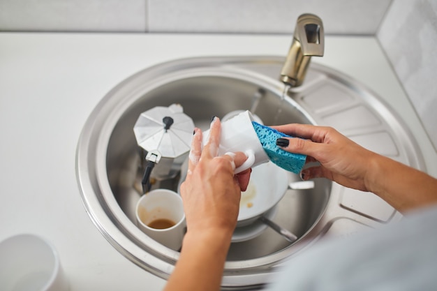 Dona de casa irreconhecível mulher lavando pratos na cozinha em casa sobre a pia, estilo de vida, equipamento da casa.