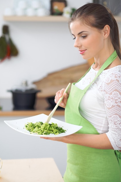 Dona de casa jovem cozinhando na cozinha conceito de refeição fresca e saudável em casa