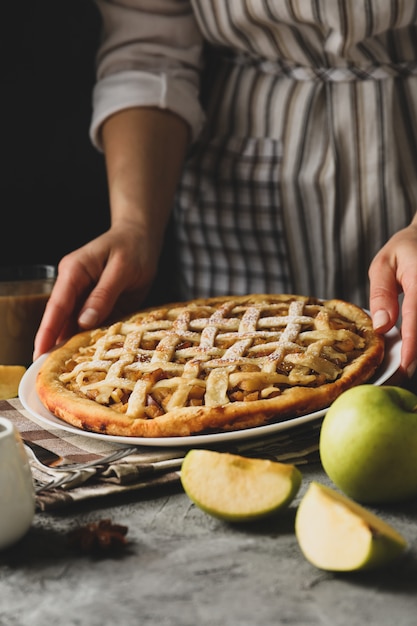 Dona de casa segura torta de maçã saborosa mesa cinza. Comida caseira