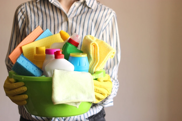 Dona de casa segura uma cesta com produtos de limpeza e desinfecção