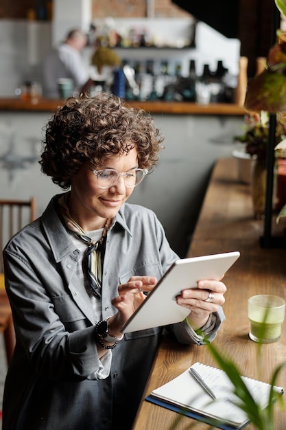 Dona de empresária sorridente do café olhando através de pedidos on-line de clientes