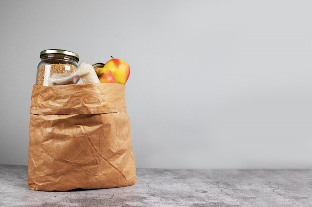 Donación de alimentos en bolsas de papel para personas aisladas sobre un fondo gris con espacio de copia. entrega de comida