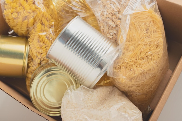 Donación Un conjunto de productos en una caja pasta mantequilla avena cereales comida enlatada fideos