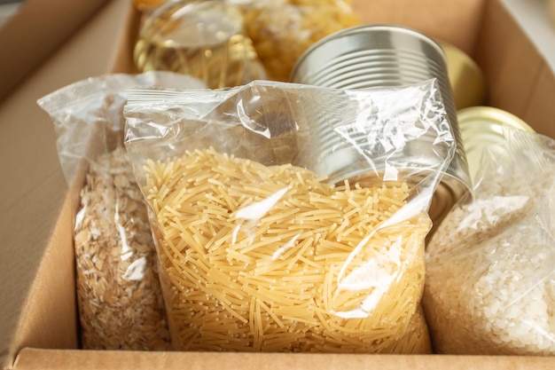 Donación a los pobres durante la epidemia de coronavirus Un conjunto de productos en una caja pasta mantequilla avena cereales comida enlatada fideos arroz