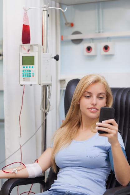 Donante de sangre femenina mirando su teléfono móvil