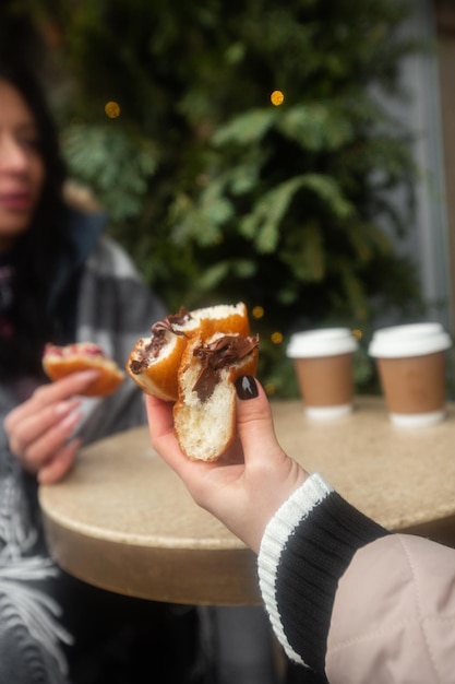 Donas alemanas berlinesas con relleno y azúcar glas en manos femeninas Niñas disfrutando de donas rellenas de chocolate y mermelada