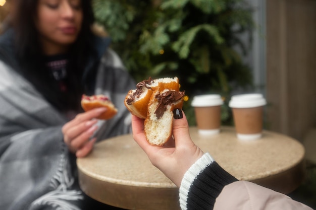 Donas alemanas berlinesas con relleno y azúcar glas en manos femeninas Niñas disfrutando de donas rellenas de chocolate y mermelada