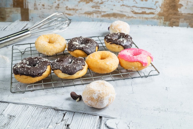 Donas de chocolate y rosquillas rosadas en la mesa de la cocina