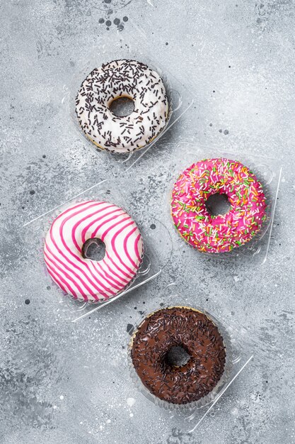 Donas glaseadas surtidas en una mesa de cocina. Fondo gris. Vista superior.