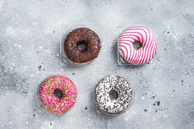 Donas glaseadas surtidas en una mesa de cocina. Fondo gris. Vista superior.