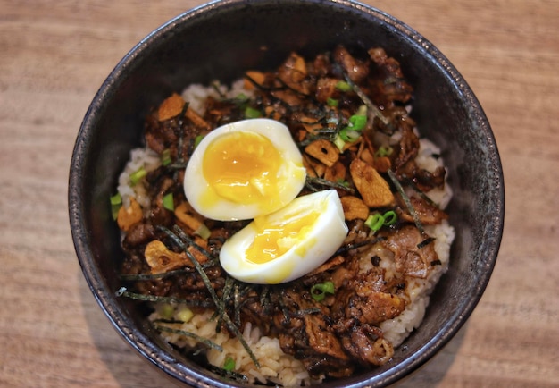 Donburi de ternera trufada Arroz japonés cubierto con ternera yakiniku chips de ajo huevo y aceite de trufa servido en la mesa