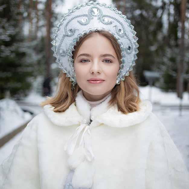 La doncella de nieve, una dulce joven rubia con un disfraz de doncella de nieve blanca con un kokoshnik y un abrigo de piel.