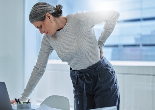 ¿Dónde está el quiropráctico cuando lo necesitas? Foto de una mujer de negocios madura que está sola en la oficina y sufre de dolor de espalda.