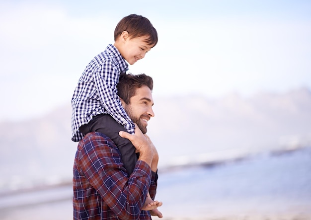 A dónde vamos ahora papá Un padre cargando a su hijo pequeño sobre sus hombros con una sonrisa