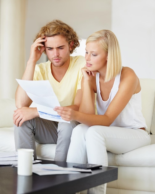 ¿De dónde vienen todas estas facturas? Una pareja joven leyendo juntos un estado financiero en su salón