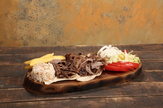 Doner kebab está acostado en la tabla de cortar Shawarma con ensalada de cebollas de carne yace en una madera oscura y vieja