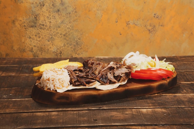 Doner kebab está deitado na tábua Shawarma com salada de cebolas de carne está em uma madeira velha escura
