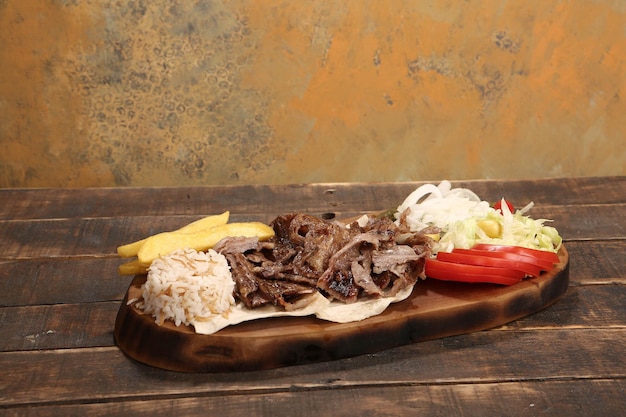 Doner kebab está deitado na tábua Shawarma com salada de cebolas de carne está em uma madeira velha escura