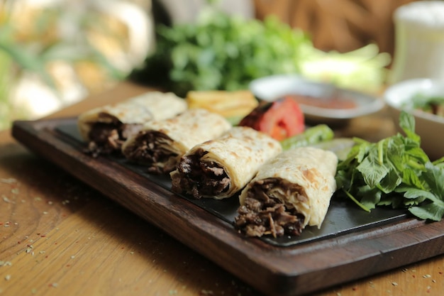 Doner kebab está tirado en la tabla de cortar. Shawarma con carne, cebolla, ensalada yace sobre una madera oscura y vieja