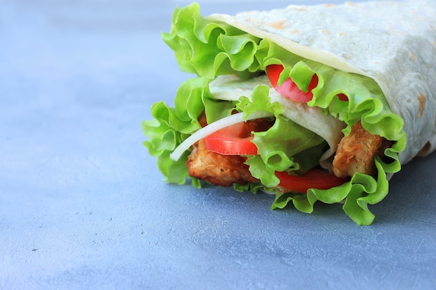 Foto doner kebab. shawarma com carne, cebola, salada e tomate em fundo cinza.