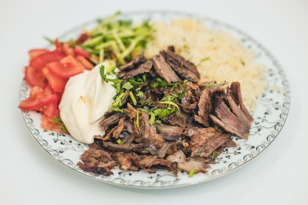 Doner o shawarma llamado pilav ustu sobre arroz con yogur, tomates y hierbas