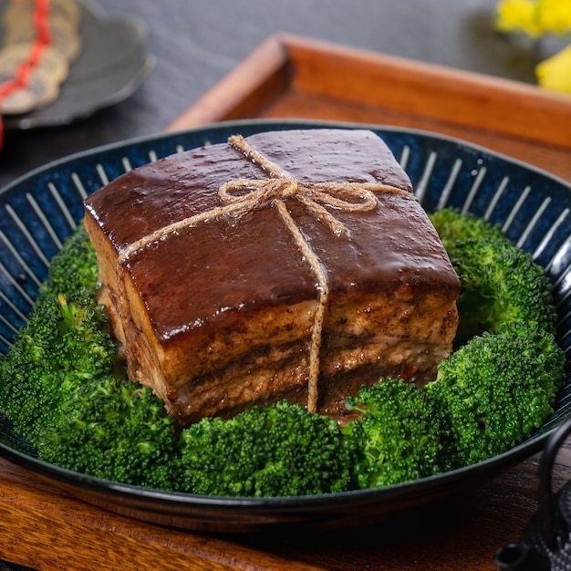 Dong Po Rou (carne de cerdo Dongpo) en un hermoso plato azul con verduras de brócoli verde