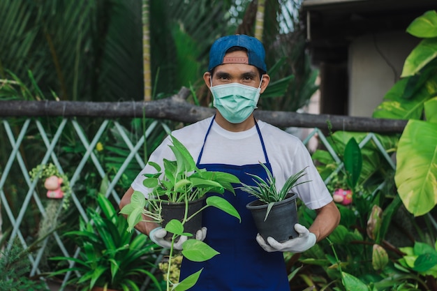 Dono de uma loja de jardinagem usa máscara para trabalhar em uma floricultura