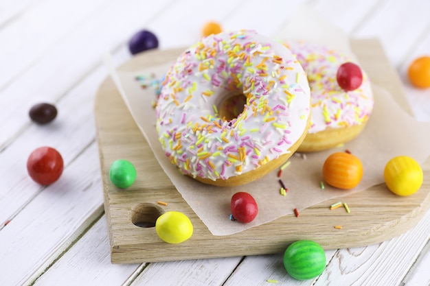 Donut auf einem hölzernen weißen Hintergrund und eine Streuung von süßen Ornamenten