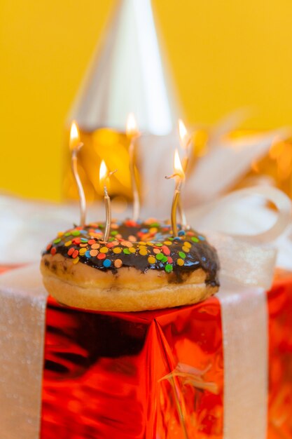 Donut de chocolate dulce y velas encendidas sobre un fondo bokeh festivo. Concepto de feliz cumpleaños.