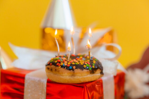 Donut de chocolate dulce y velas encendidas sobre un fondo bokeh festivo. Concepto de feliz cumpleaños.