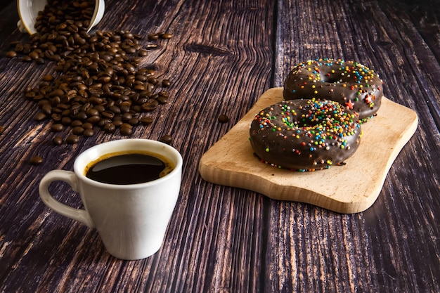 Donut de chocolate con glaseado y una taza de café sobre la mesa