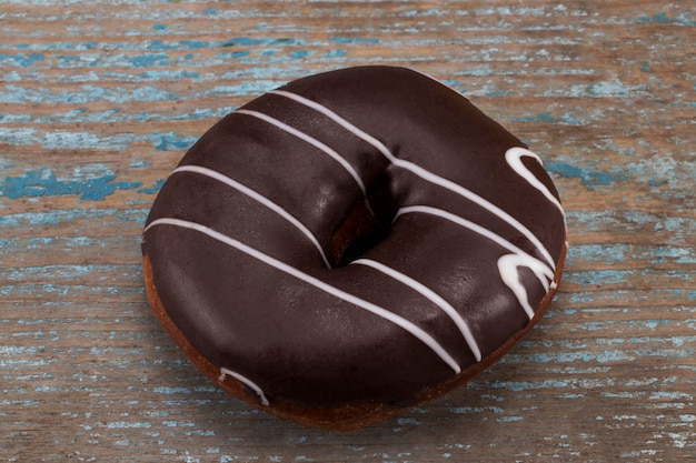 Donut de chocolate con rayas blancas sobre fondo de madera.