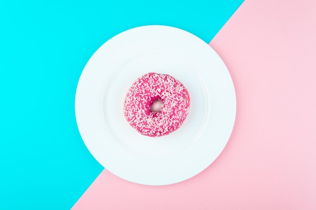 Donut cubierto con glaseado en la vista superior del plato Foto en una combinación de colores rosa y azul