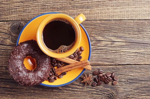 Donut de chocolate e café na mesa de madeira