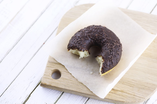 Donut de chocolate em um fundo branco de madeira e vários enfeites doces