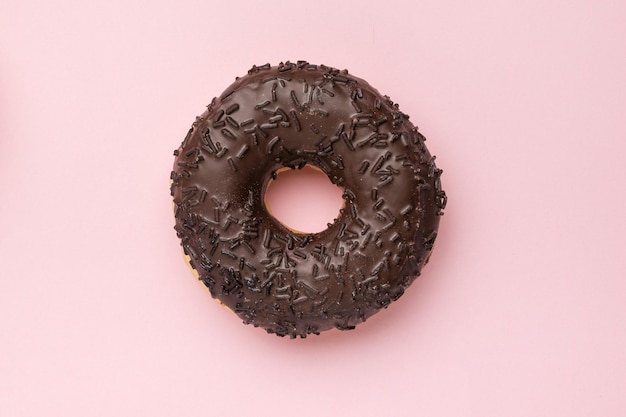 Donut de chocolate escuro em um fundo rosa o conceito mínimo de cozimento popular